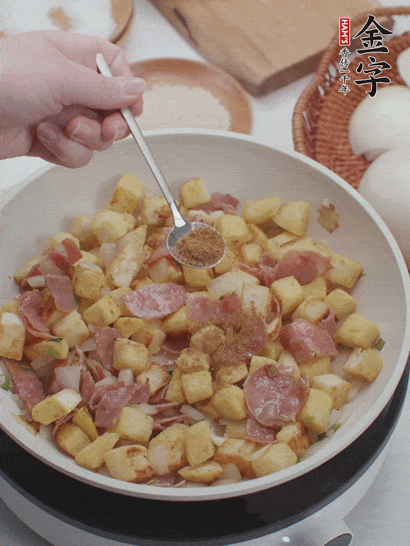起鍋少油，煸香洋蔥丁、蔥白，加入金字培根火腿翻炒幾下，再加入饅頭丁、1小勺孜然粉、少許鹽翻炒均勻并鋪平。